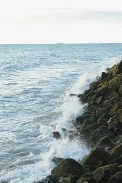 Waves flowing on the rocks covered in moss at the beach Stock Photos