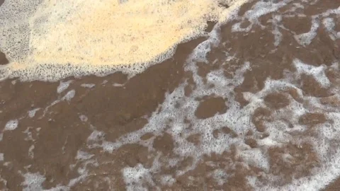 Waves forming foam, when it touches the brown sands Video stock 96711929