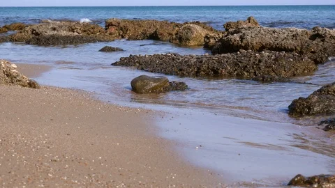 Waves gentling lapping on sandy and rocky beach Stock Footage 98180287