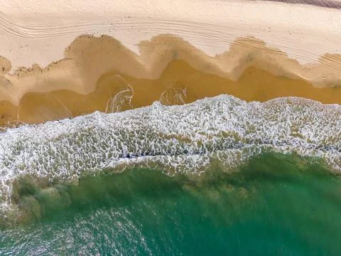 Waves gently break on sandy beach during sunny day near tropical shore with.. Stock Photos