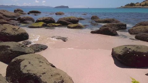 Waves gently breaking on a rocky shoreline of a tropical beach Stock Footage 125113899