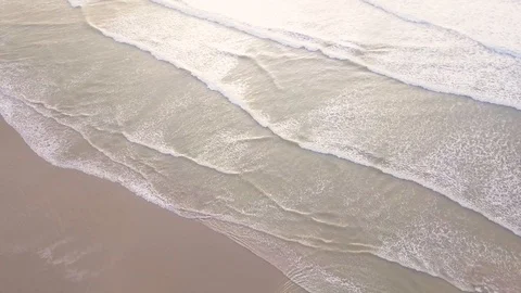 Waves gently breaking on to a sandy beach in the sun Video stock 114559052