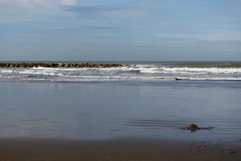Waves gently crash against a stone breakwater Stock Photos