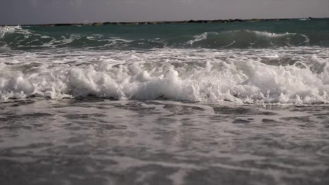 Waves gently crash on the sandy beach shore, a serene seaside atmosphere Video stock 278159344