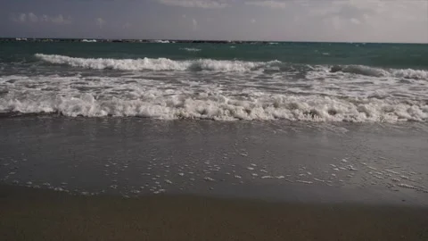 Waves gently crash on the sandy beach shore, a serene seaside atmosphere Video stock 280124318