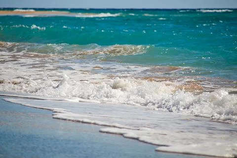 Waves gently crash onto the sandy beach Stock Photos