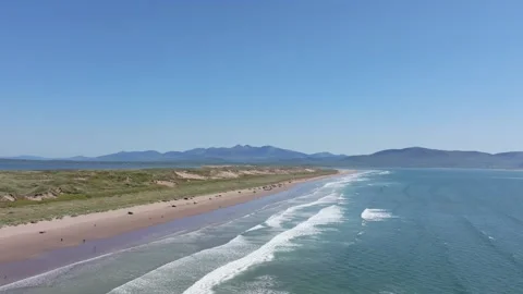 Waves Gently Crashing on Sandy Shoreline with Distant Mountains in View Vídeos de archivo 337036758