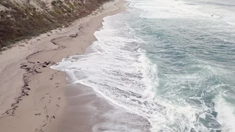 Waves gently crashing on a serene beach with lush green hills in the background Stock Footage 285676783