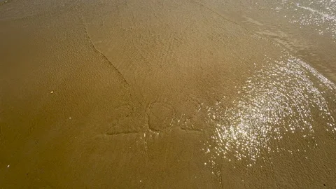 Waves gently erase "2024" from the sand, marking the start of a new year. Stock Footage 287385636