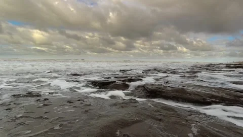 Waves gently hitting rocks on a beach. Beautiful sky with many clouds. Stock Footage 252399340