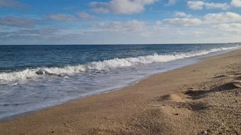 Waves gently hitting sandy beach under autumn blue sky Stock Footage 321180968