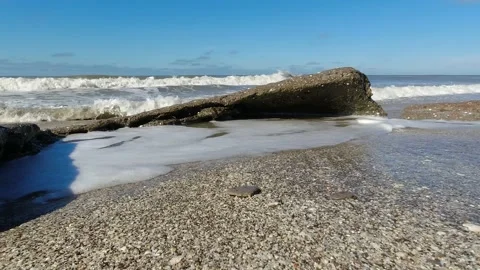 Waves gently hitting stones on the seashore. Clear sky. Stock Footage 170888331