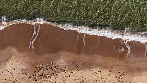 Waves gently kiss the sandy shore at sunset, creating a serene atmosphere filled Stock Footage 332042476