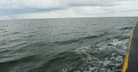 Waves gently lap against a shoreline at dusk near a tranquil body of water Stock Footage 281816902