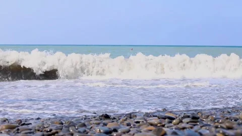 Waves gently lap against smooth pebbles on a serene beach Stock Footage 309191666