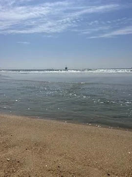 Waves Gently Lap Against Sun-Soaked Sand at the Tranquil Beachside Stock Photos