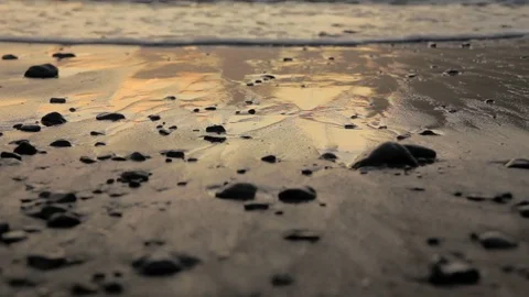 Waves gently lap over glistening sand and stones Stock Footage 71124731