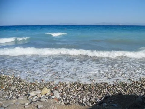 Waves gently lap on a pebbly beach in Greece 写真素材