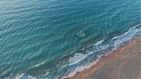 Waves gently lap on the sandy shore during a calm afternoon at the beach Stock Footage 290097563