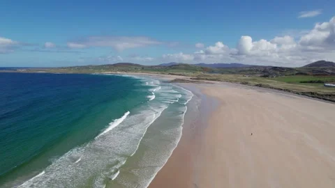 Waves gently lap the sandy shore of a scenic beachin Donegal on a sunny day Stock Footage 310240480