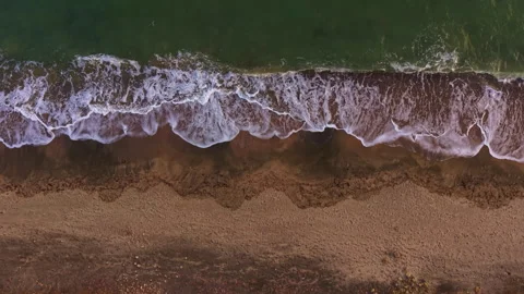 Waves gently lap the shore as sunlight dances on the water at a serene beach Stock Footage 331975327