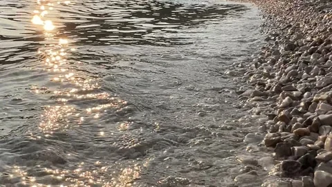 Waves Gently Lapping on Pebble Beach at Sunset Stock Footage 280053913
