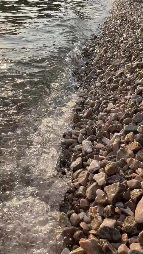 Waves Gently Lapping on Pebble Beach at Sunset Stock Footage 280054048