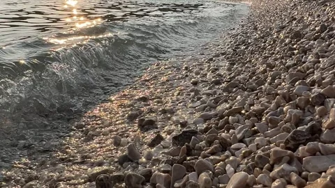Waves Gently Lapping on Pebble Beach at Sunset Stock Footage 280054161