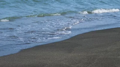 Waves gently lapping the sandy beach on a tranquil summer day Vidéo 301920757