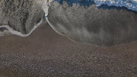 Waves gently lapping the shore on a sandy beach.Low overhead drone footage in Stock Footage 341111880