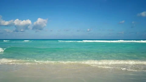 Waves gently roll onto the sandy beach on a sunny day Stock Footage 312482365