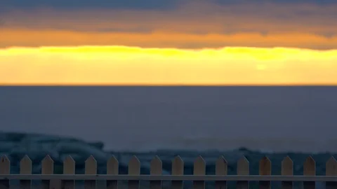 Waves Gently Rolling in Behind a Fence During a Golden Sunset Stock Footage 96008584