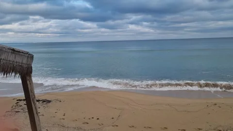 Waves gently rolling onto sandy beach under dramatic cloudy coastal sky Stock Footage 322124795