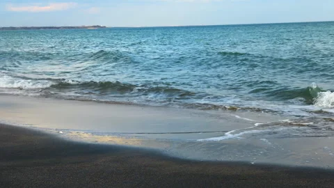 Waves gently touch the shore of a beach near the ocean during the evening Stock Footage 327613289