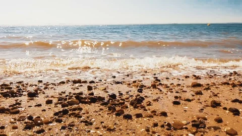 Waves gently washing over a golden sandy beach Stock Footage