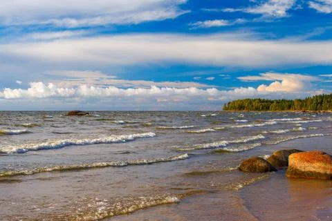 Waves, granite stone, evening clouds. Evening landscape on the Gulf of Finlan Stock Photos