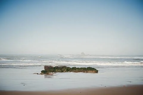 Waves have broken over a flat rock, covering it in white water. A cluster of  Stock Photos