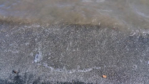 Waves from a height crash against a beach with sand at sunset Video stock 243208920
