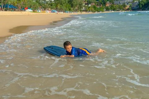 The waves hit the boy on the surfboard toward the shore. Stock Photos