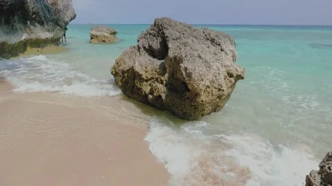 The waves hit the waves in the cracks of the rocks and surged on the beach. 動画素材 130903132