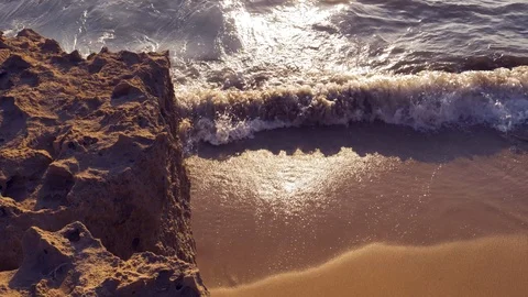 Waves hitting a beach filmed off a cliff side Stock Footage 114713302