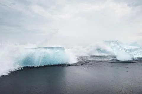 Waves hitting clear blue blocks on the black sand beach, iceland Stock Photos
