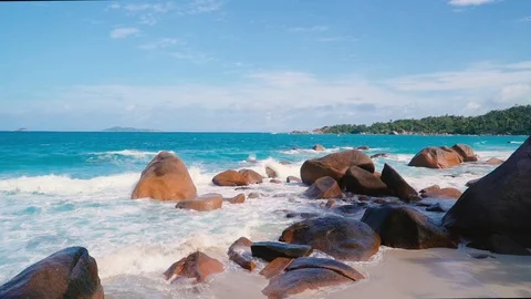 Waves hitting the granite rocks on a sandy beach on Praslin, Seychelles. Stockbeeldmateriaal 107562148