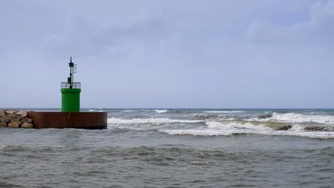 Waves hitting green lighthouse tower of a harbor entrance. Stock Footage 94519467