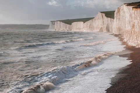 Waves hitting the pebble beach by Seven Sisters chalk cliffs in East Sussex,  Stock Photos