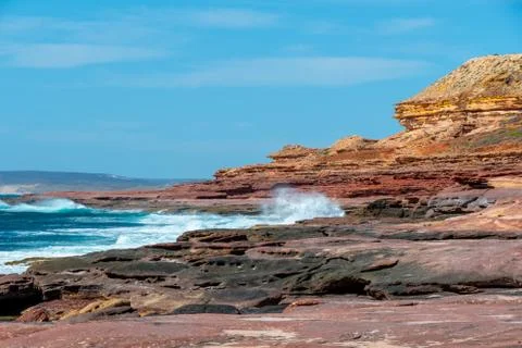 Waves hitting rock coast with different colors from red to yellow in the Kalb Stock Photos
