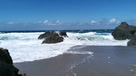 Waves hitting rocks and generating foam at the beach Stock Footage 132038877