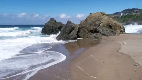 Waves hitting rocks and generating foam at the beach Stock Footage 132038954