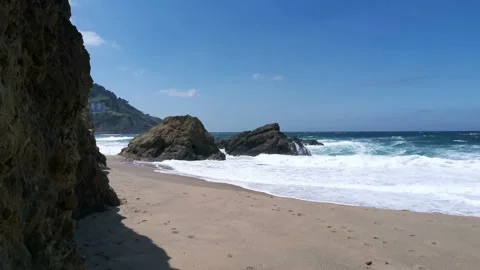 Waves hitting rocks and generating foam at the beach Stock Footage 132039042