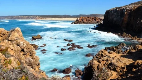 Waves hitting the rocks, Carrapateira, in the background beach Praia da Bordeira Stock Footage 87327247